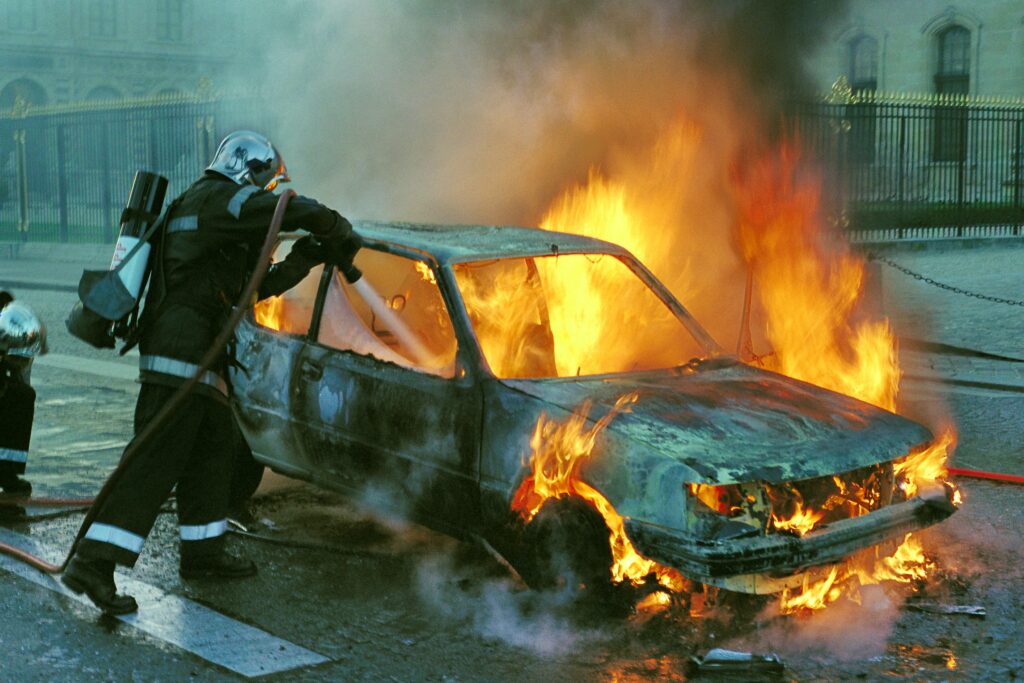 a fire fighter trying to extinguish a burning car